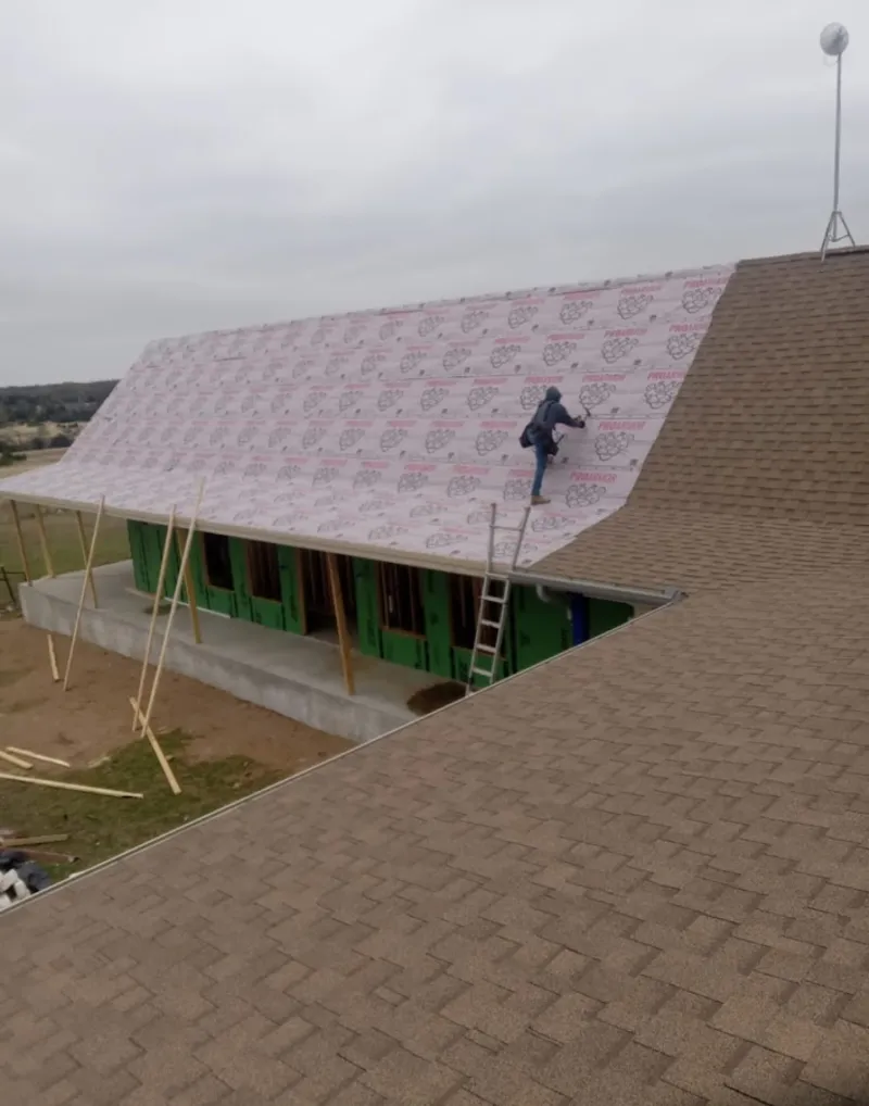 Worker preparing underlayment for a metal roof installation in College